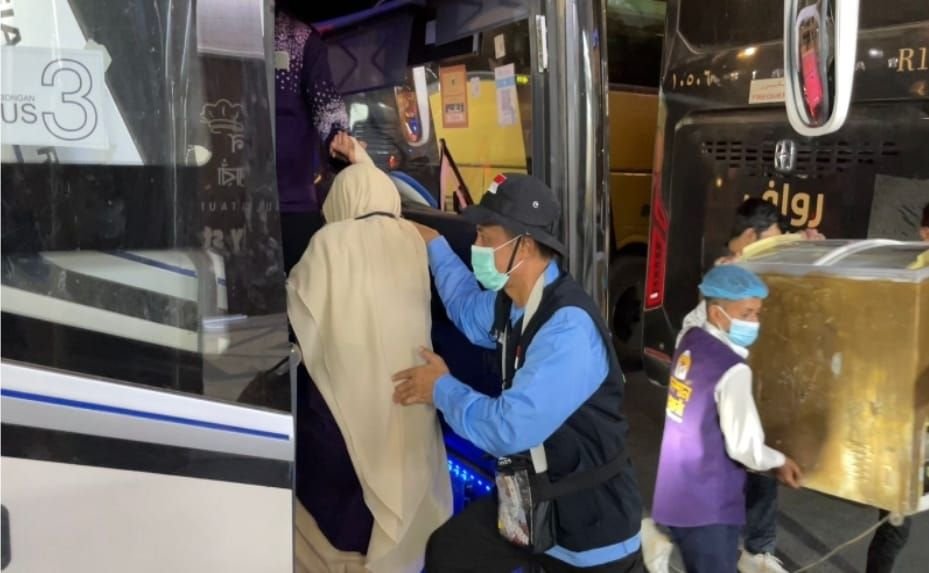 Momen jemaah haji yang akan masuk ke dalam bus dibantu oleh petugas.