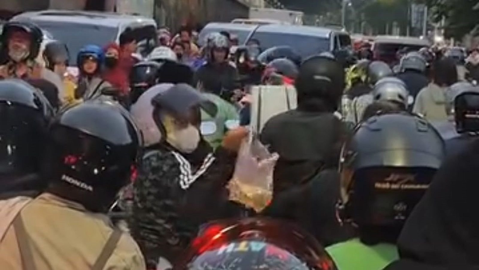 Pengendara motor saling berbagi makanan di waktu buka puasa saat terjebak macet.